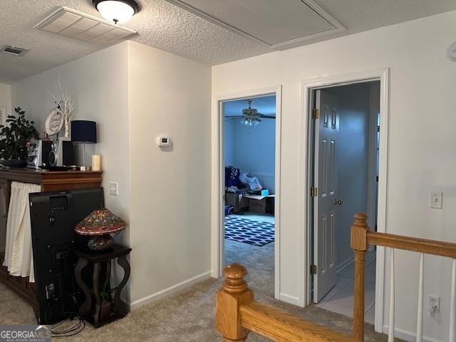 hall with light carpet and a textured ceiling