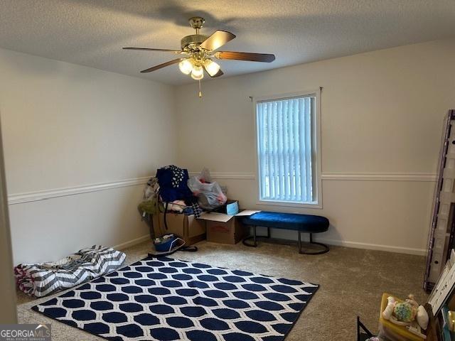 miscellaneous room featuring ceiling fan, carpet flooring, and a textured ceiling