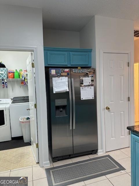 kitchen featuring blue cabinets, stainless steel refrigerator with ice dispenser, light tile patterned floors, and washing machine and dryer