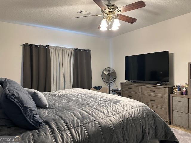 bedroom with ceiling fan and a textured ceiling