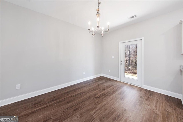 empty room with dark hardwood / wood-style floors and a chandelier