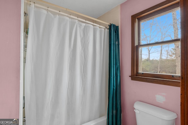 bathroom featuring shower / bathtub combination with curtain and toilet