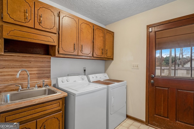 washroom with cabinets, washer and clothes dryer, sink, and a textured ceiling