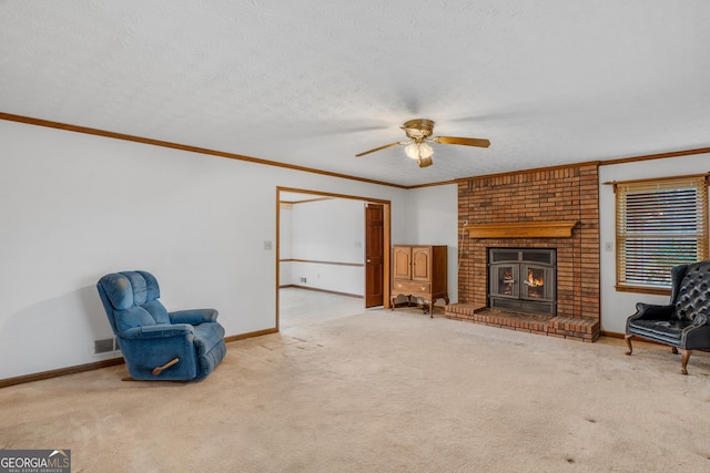 living area featuring a fireplace, ornamental molding, light colored carpet, ceiling fan, and a textured ceiling