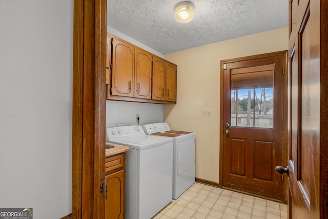 laundry room featuring cabinets, washing machine and dryer, and a textured ceiling