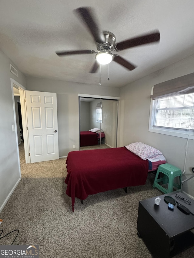 carpeted bedroom with ceiling fan, a closet, and a textured ceiling