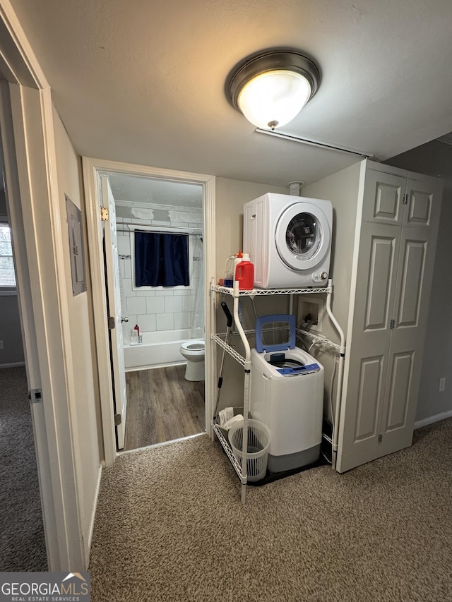 clothes washing area featuring stacked washer / drying machine and carpet flooring