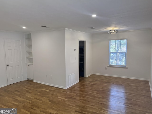 empty room featuring dark hardwood / wood-style flooring, built in shelves, and ornamental molding