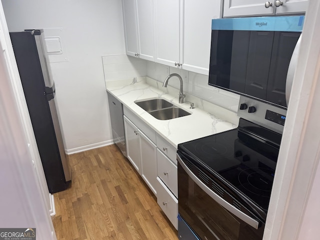 kitchen featuring appliances with stainless steel finishes, light hardwood / wood-style floors, sink, and white cabinets