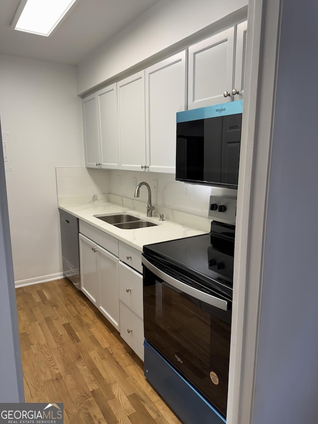 kitchen featuring electric range oven, white cabinetry, sink, stainless steel dishwasher, and light hardwood / wood-style flooring