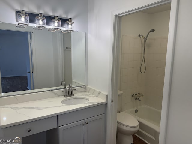 full bathroom with vanity, tiled shower / bath, and toilet