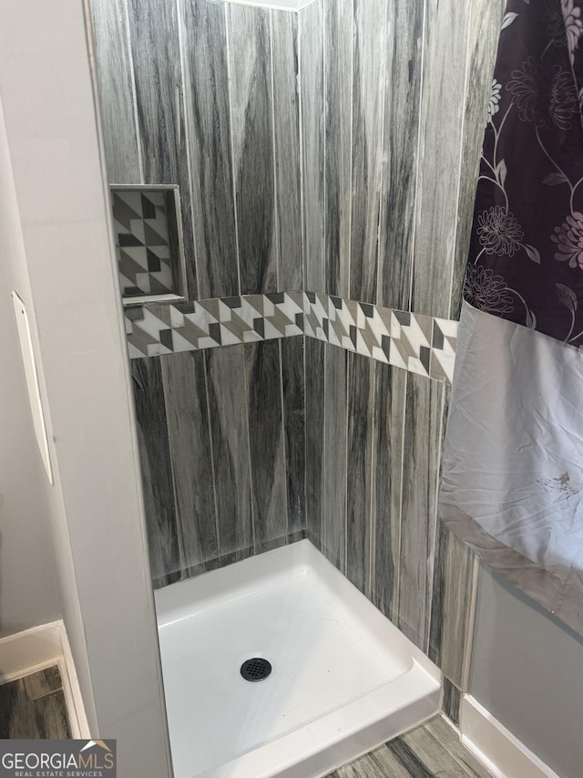 bathroom featuring a tile shower and hardwood / wood-style floors