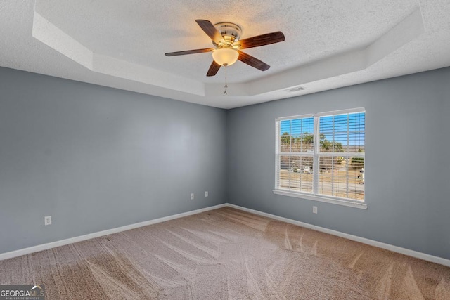 carpeted empty room with ceiling fan, a tray ceiling, and a textured ceiling