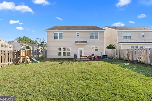 rear view of house with a playground, a yard, and central AC unit