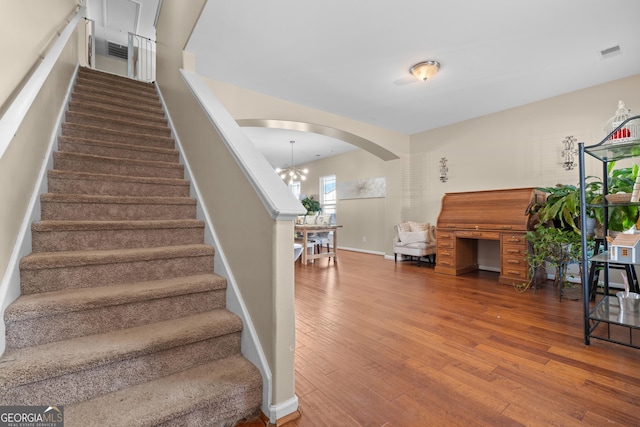 stairway with an inviting chandelier and hardwood / wood-style flooring