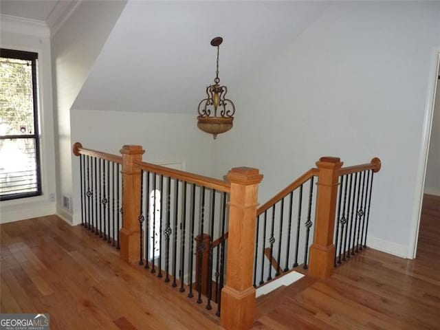 stairs with wood-type flooring, vaulted ceiling, and crown molding