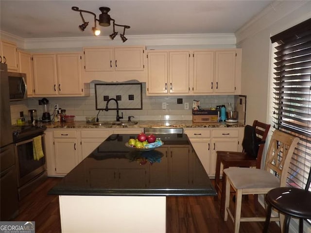 kitchen featuring sink, appliances with stainless steel finishes, a center island, ornamental molding, and dark hardwood / wood-style flooring