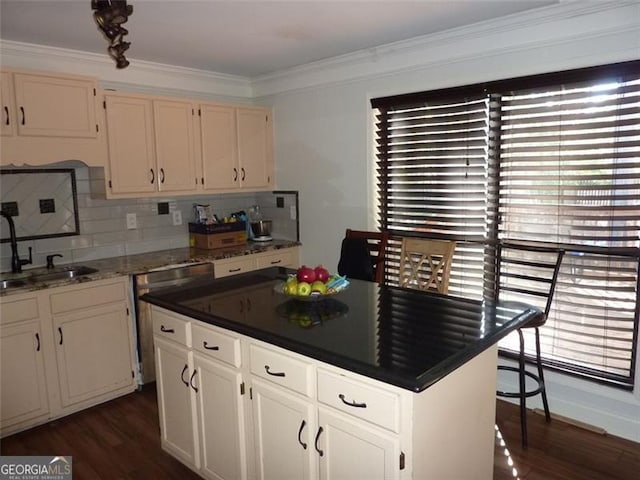 kitchen with dark wood-type flooring, sink, stainless steel dishwasher, ornamental molding, and white cabinets