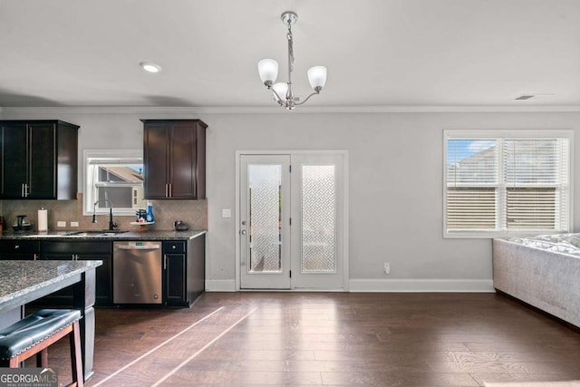 kitchen featuring decorative light fixtures, sink, stainless steel dishwasher, light stone counters, and dark brown cabinets