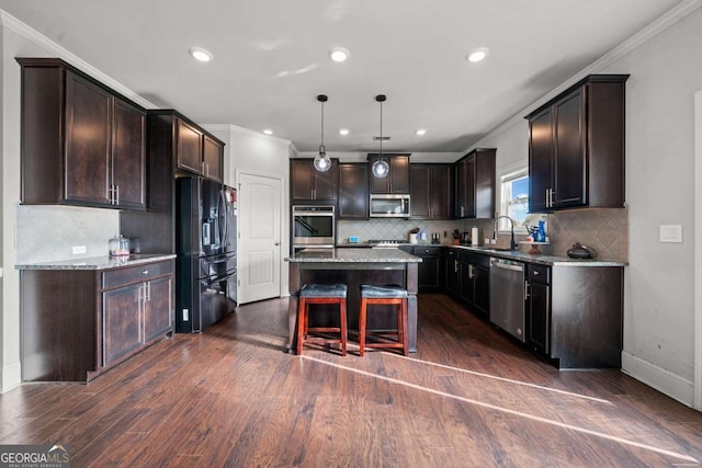 kitchen featuring pendant lighting, a kitchen breakfast bar, a center island, light stone counters, and stainless steel appliances