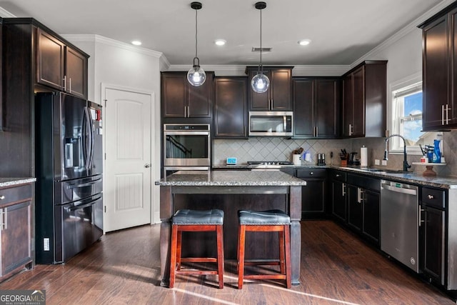 kitchen with decorative light fixtures, sink, dark stone countertops, a center island, and stainless steel appliances