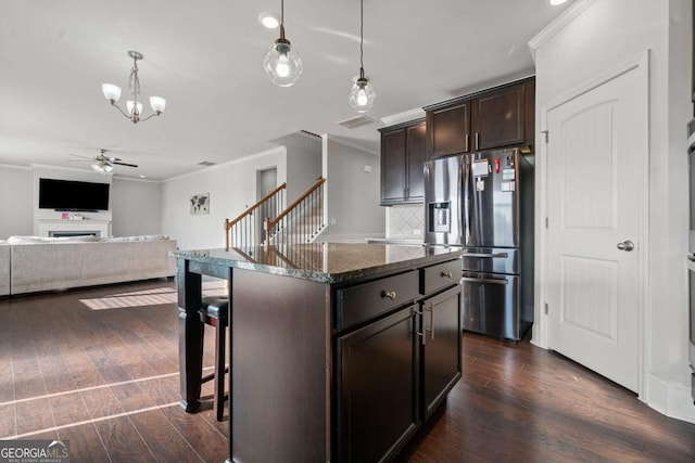 kitchen with pendant lighting, dark brown cabinetry, a center island, and stainless steel fridge with ice dispenser