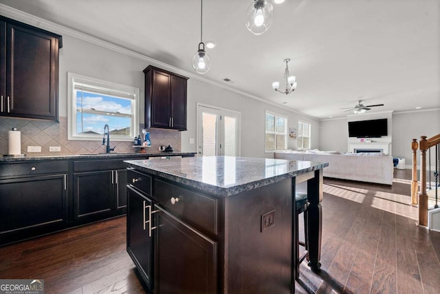 kitchen with hanging light fixtures, a kitchen island, dark hardwood / wood-style floors, and dark brown cabinets