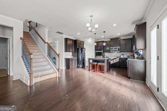 kitchen featuring appliances with stainless steel finishes, a breakfast bar, decorative light fixtures, a center island, and dark brown cabinets