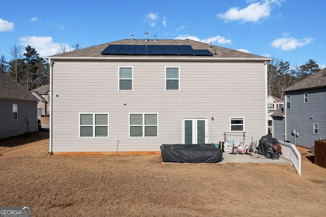 rear view of property with a yard, a patio, and solar panels