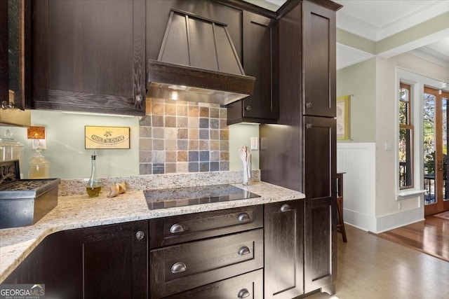 kitchen featuring premium range hood, black electric stovetop, light stone countertops, and dark brown cabinets