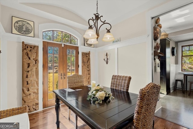 dining area featuring dark hardwood / wood-style flooring, a notable chandelier, lofted ceiling, and french doors