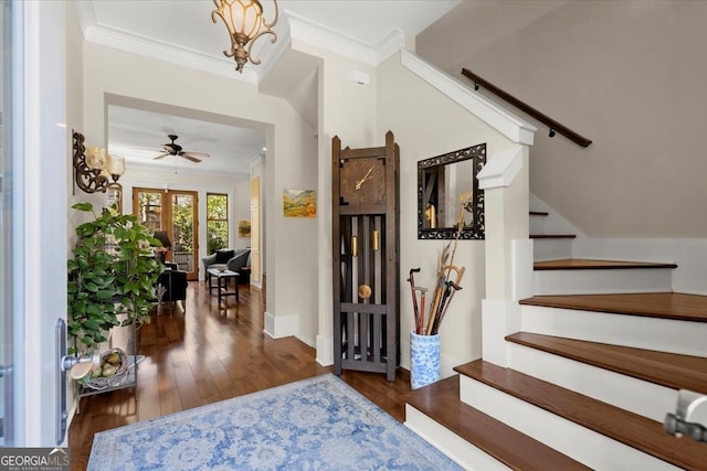 foyer with crown molding, ceiling fan with notable chandelier, and dark hardwood / wood-style flooring