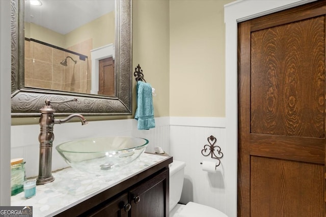 bathroom with vanity, tiled shower, and toilet