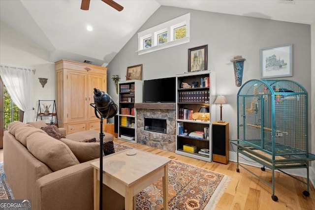 living room featuring light hardwood / wood-style flooring, a fireplace, high vaulted ceiling, and ceiling fan