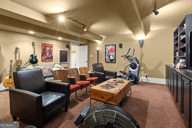 recreation room featuring track lighting, beamed ceiling, and dark colored carpet