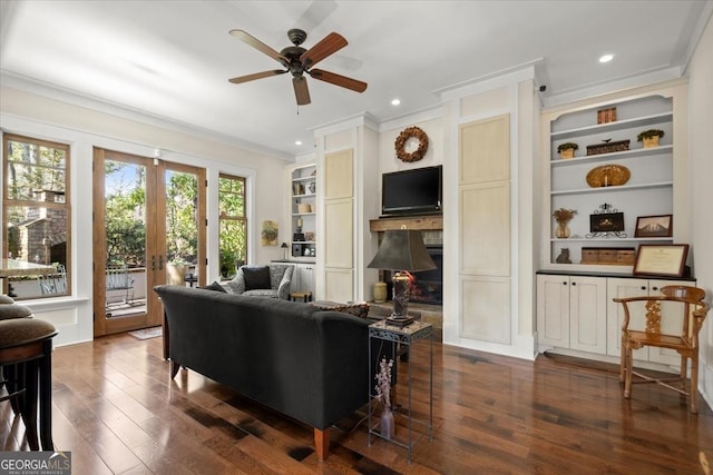 living room with crown molding, dark hardwood / wood-style floors, built in features, and a fireplace