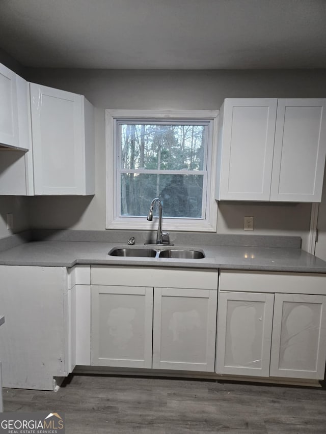 kitchen with sink, wood-type flooring, and white cabinets