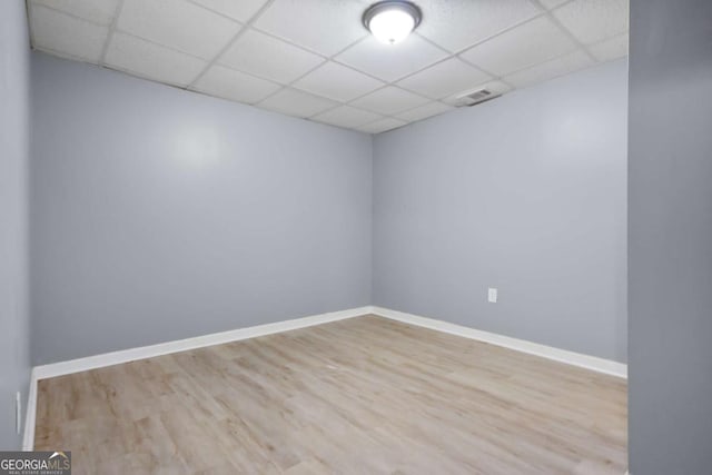 empty room with a paneled ceiling and light hardwood / wood-style flooring