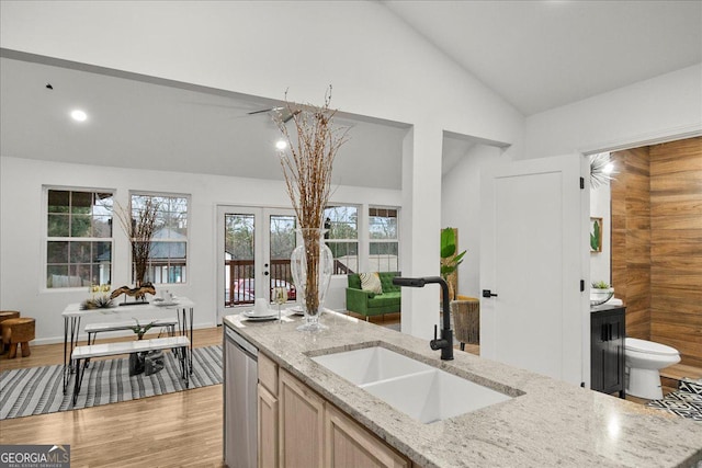 kitchen featuring lofted ceiling, light brown cabinetry, sink, and light stone countertops