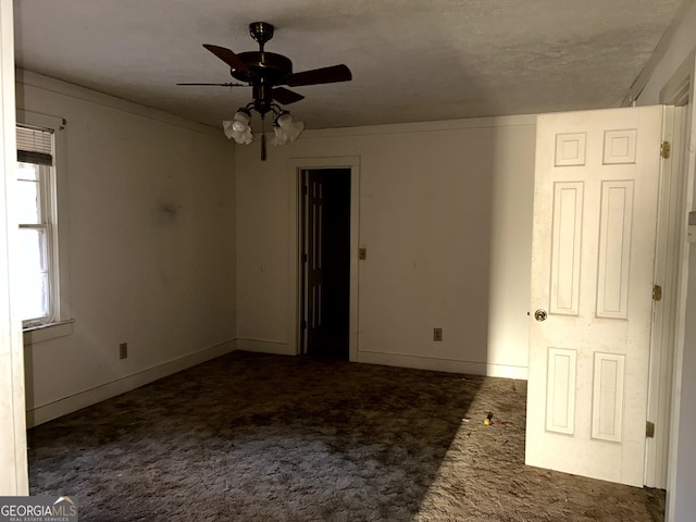 empty room with ceiling fan and dark carpet