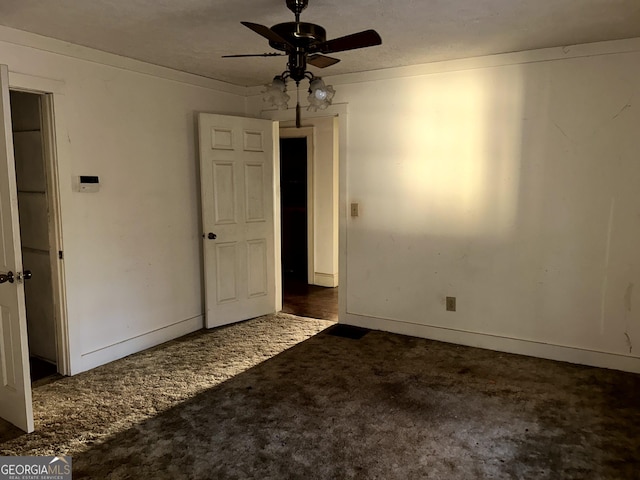 empty room with ceiling fan, a textured ceiling, and dark colored carpet