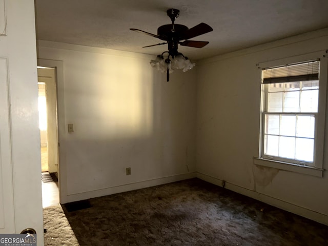 spare room featuring ceiling fan and dark colored carpet