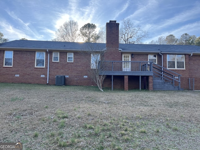 rear view of house with a wooden deck, central AC unit, and a lawn