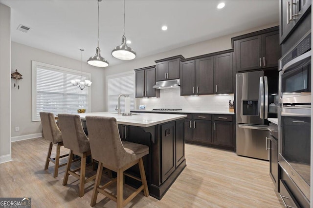 kitchen with pendant lighting, sink, a kitchen island with sink, tasteful backsplash, and stainless steel fridge with ice dispenser