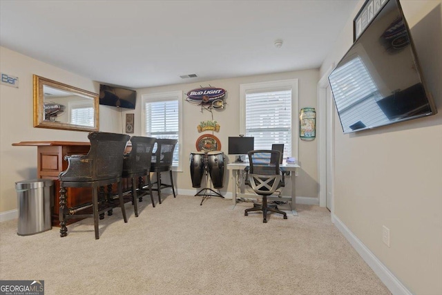 home office with light colored carpet and bar