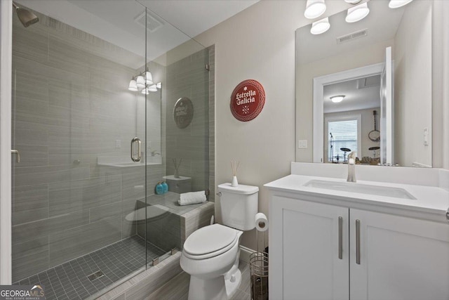 bathroom featuring vanity, a shower with shower door, and toilet