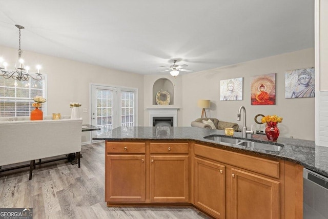 kitchen featuring ceiling fan with notable chandelier, decorative light fixtures, dishwasher, sink, and dark stone countertops