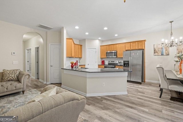 kitchen featuring sink, hanging light fixtures, light hardwood / wood-style floors, kitchen peninsula, and stainless steel appliances