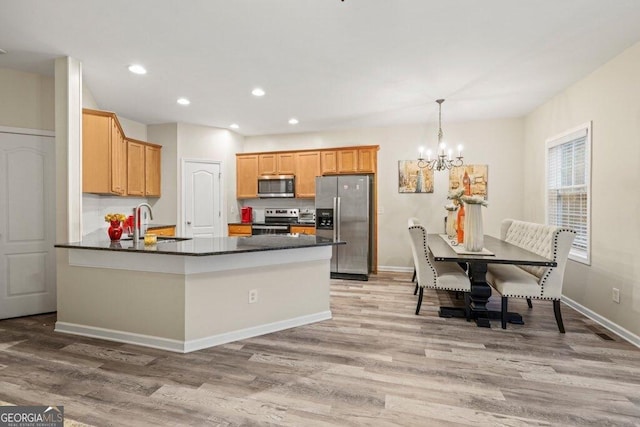 kitchen featuring pendant lighting, sink, appliances with stainless steel finishes, kitchen peninsula, and a chandelier