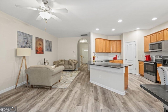 kitchen featuring appliances with stainless steel finishes, kitchen peninsula, sink, and light wood-type flooring